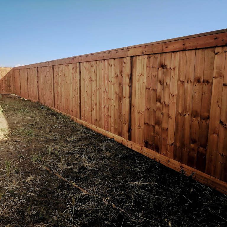 Wooden privacy fence in a yard against a blue sky.