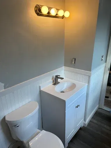 A bathroom with a toilet , sink and vanity.