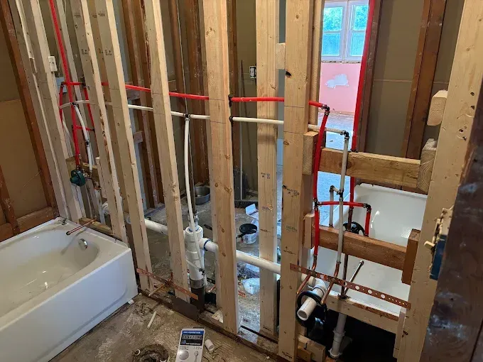 A bathroom under construction with a bathtub and pipes.
