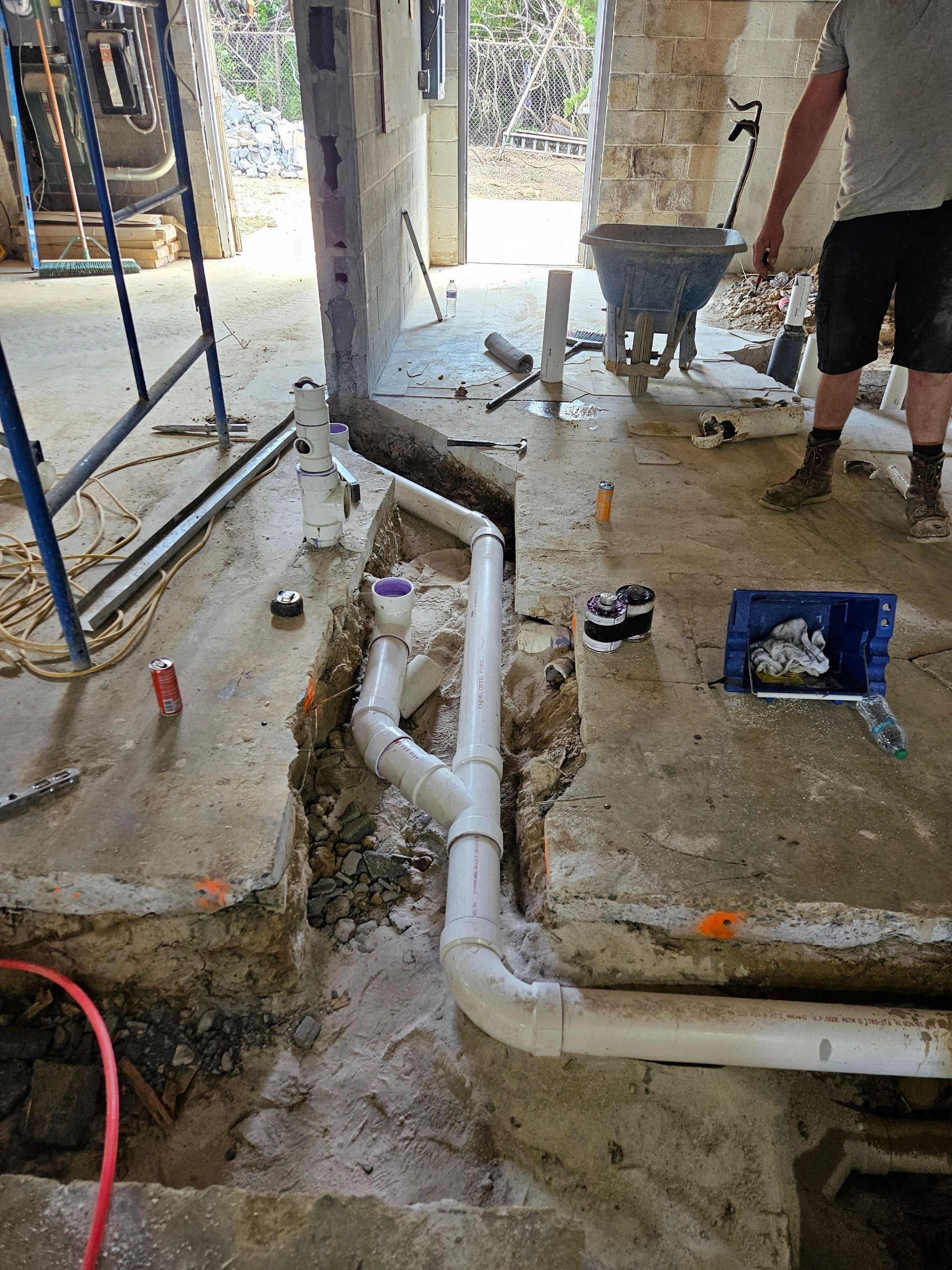 A man is working on a pipe in a hole in the ground.
