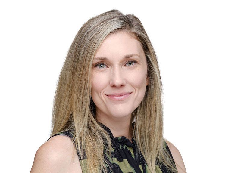 A woman with long blonde hair is smiling for the camera.