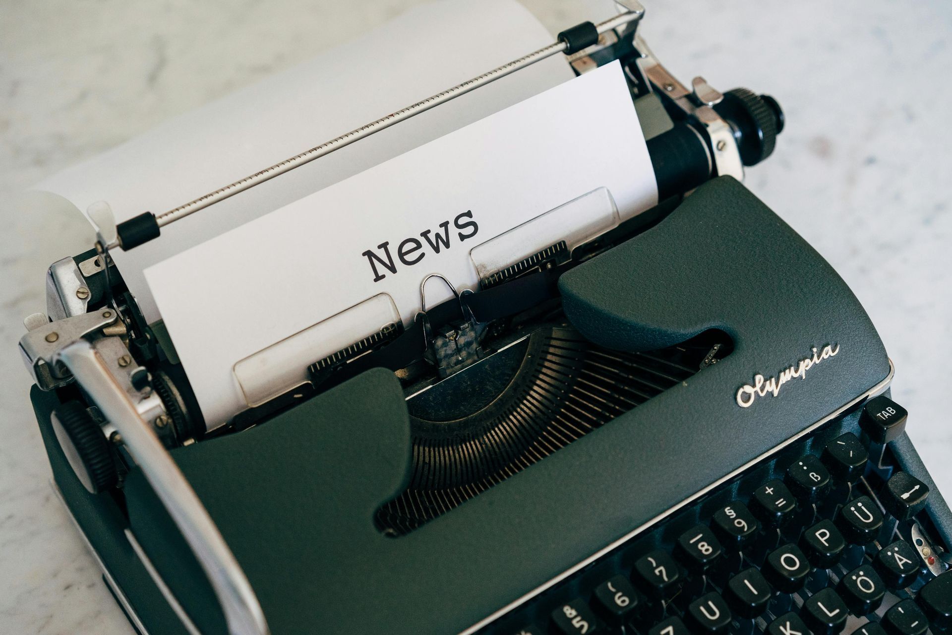 A typewriter with a piece of paper that says news on it.