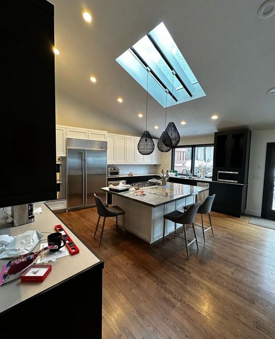 A kitchen with stainless steel appliances , a large island , and a skylight.