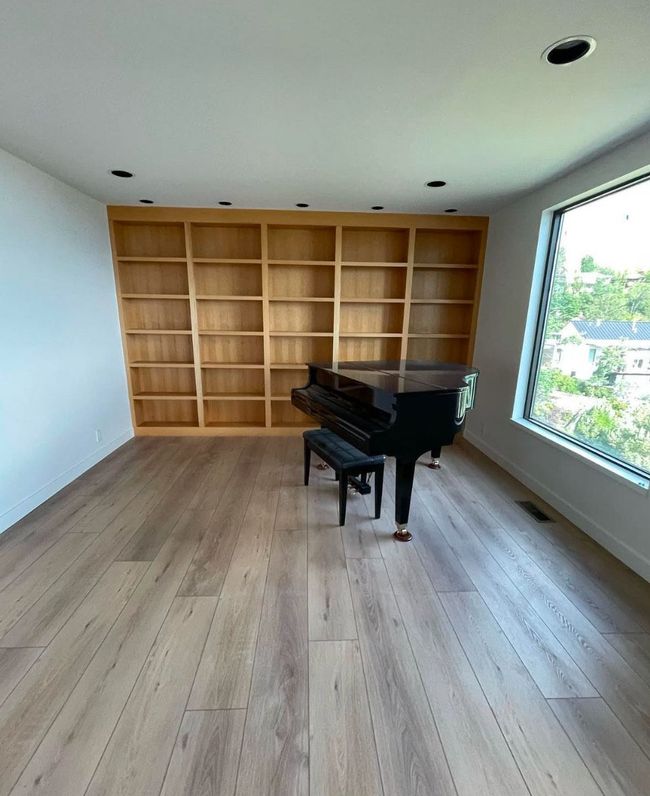 An empty room with a piano and shelves