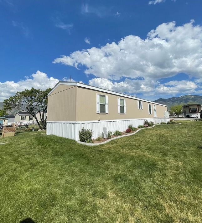 A mobile home is sitting in the middle of a lush green field.