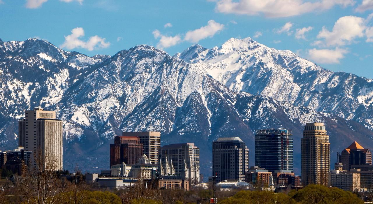 A city skyline with snow covered mountains in the background