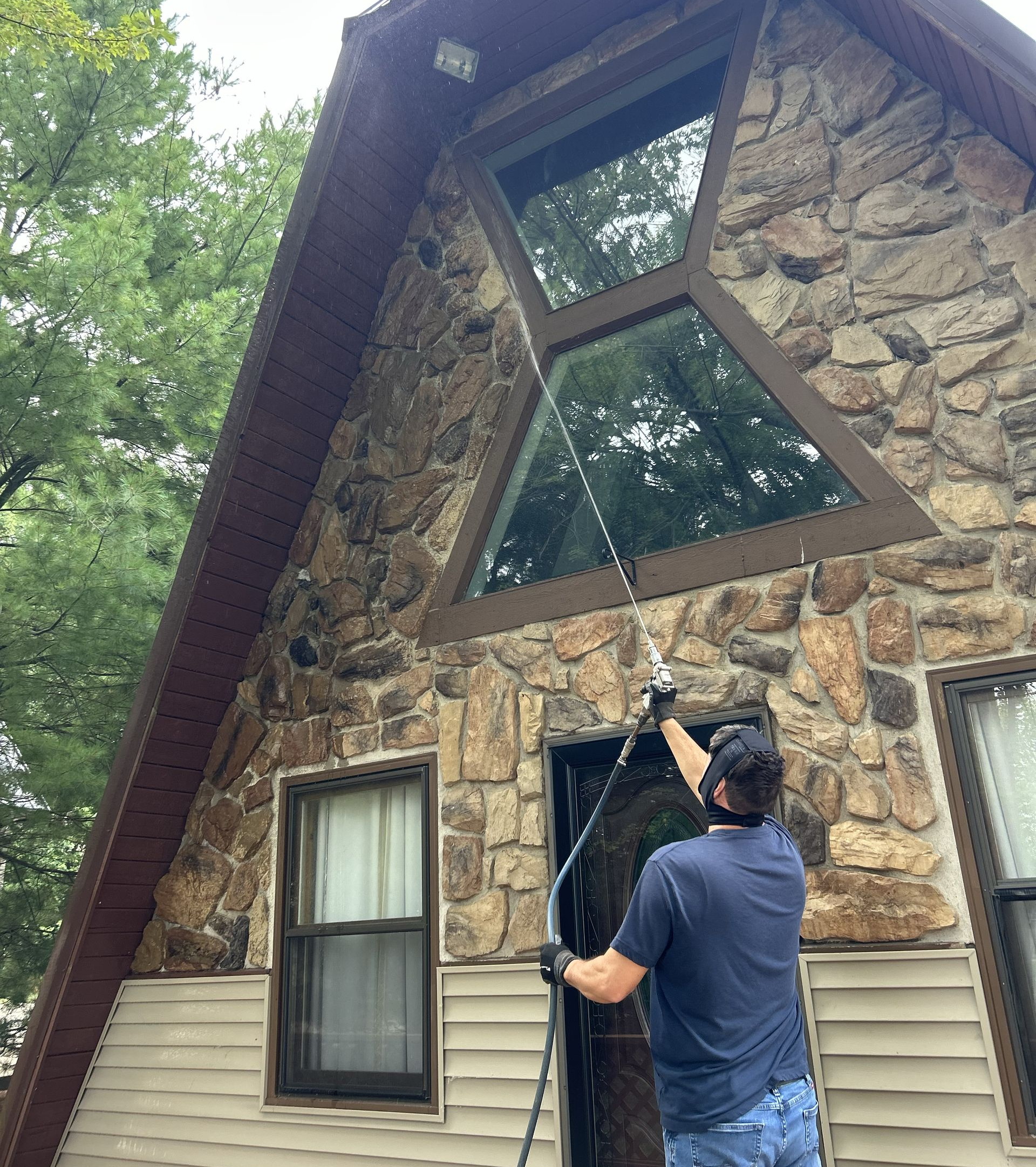 Person in protective suit spraying a floor with a pesticide. Orange tank beside.