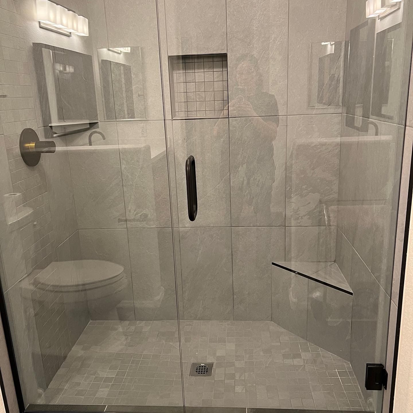 A bathroom with a toilet , sink and shower with a glass door.