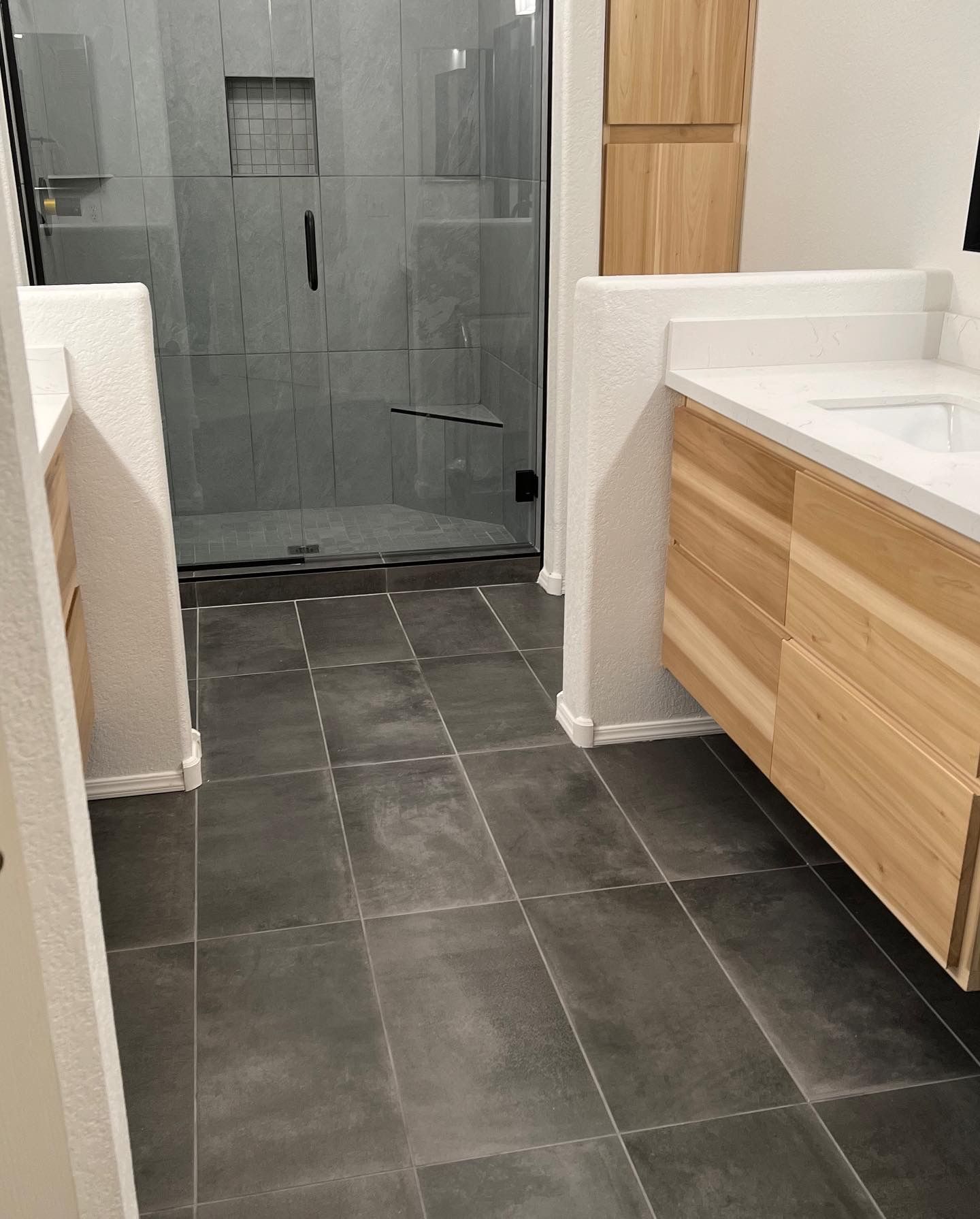 A bathroom with a walk in shower and a sink