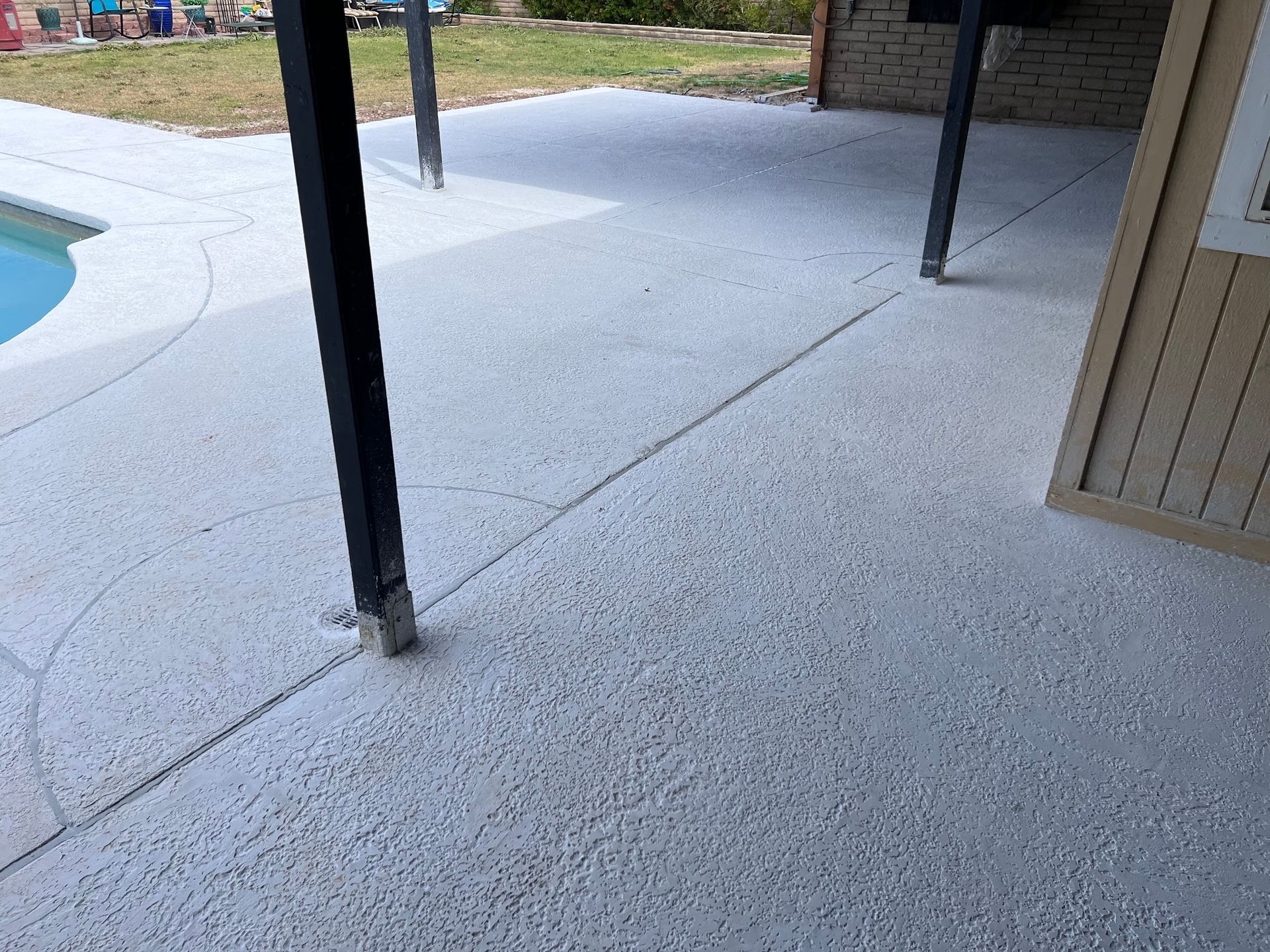 A concrete patio with a pool in the background