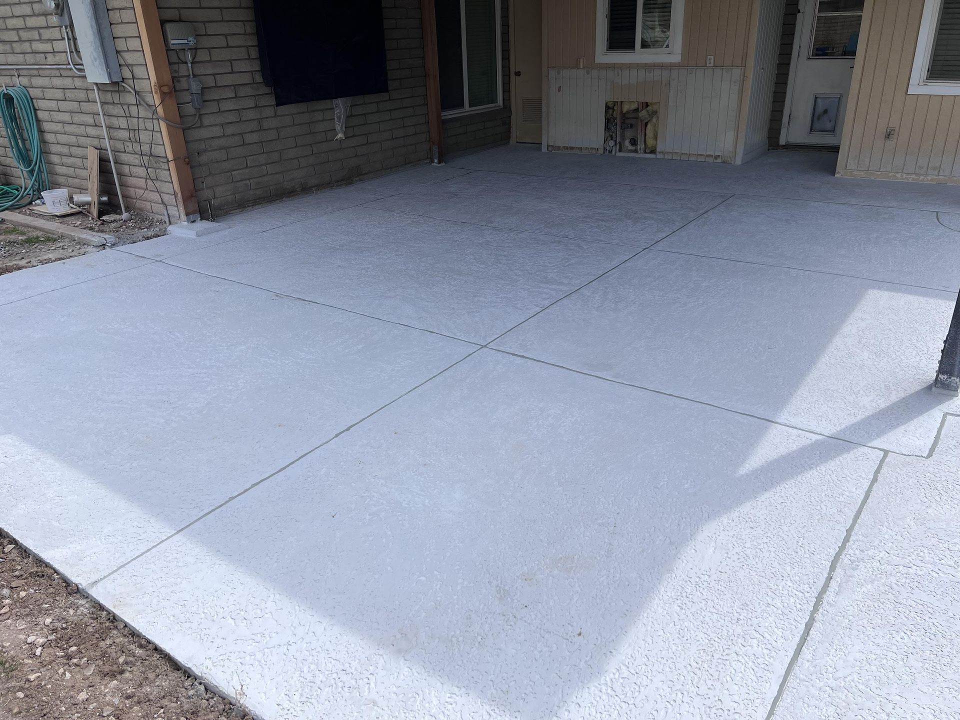 A white concrete driveway with a brick building in the background.