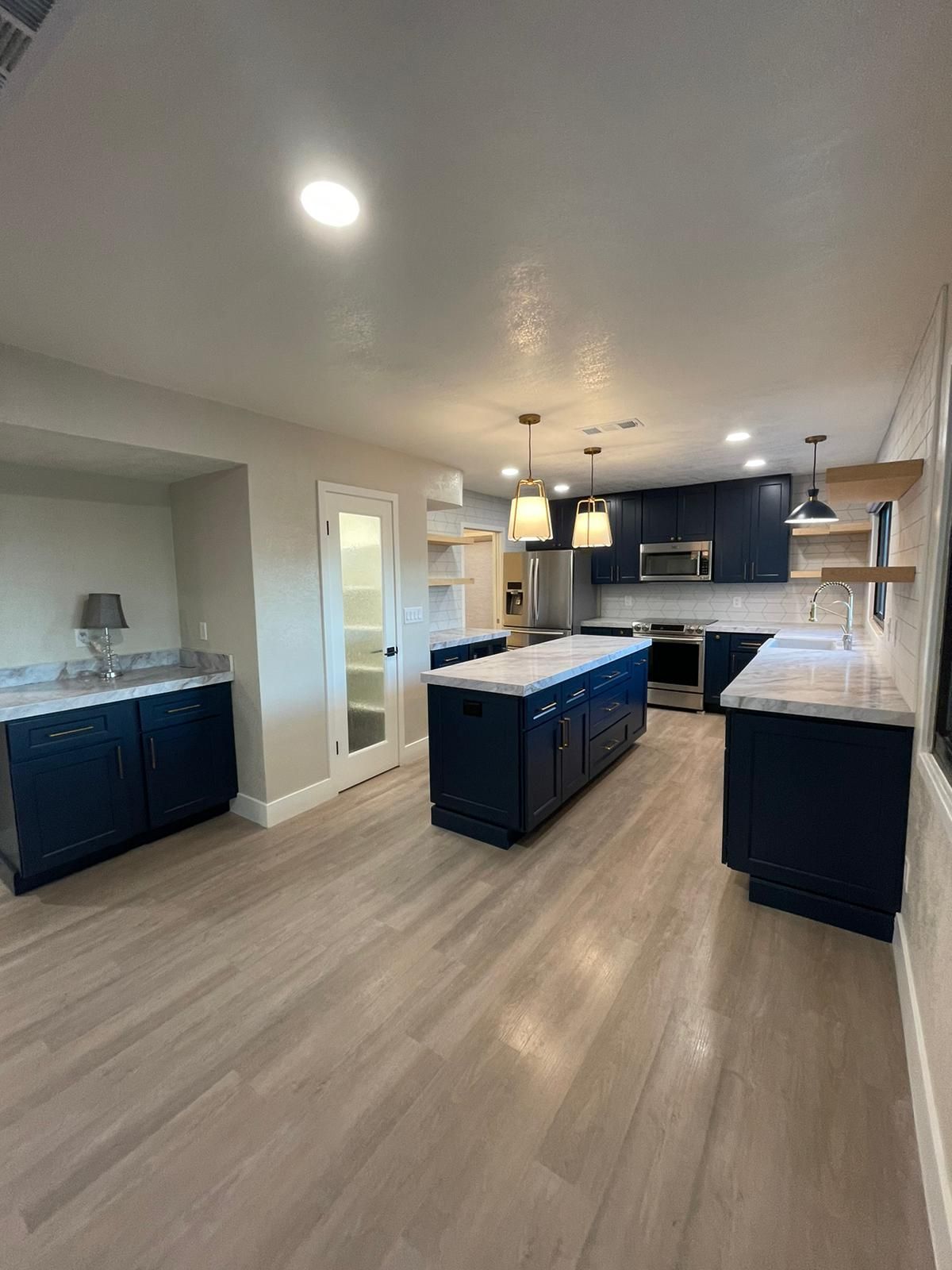 A kitchen with blue cabinets , white counter tops , and stainless steel appliances.
