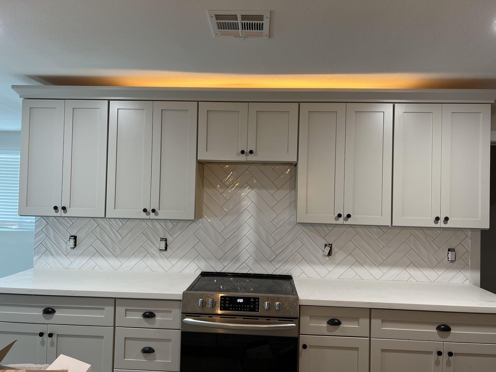 A kitchen with white cabinets and a stove top oven