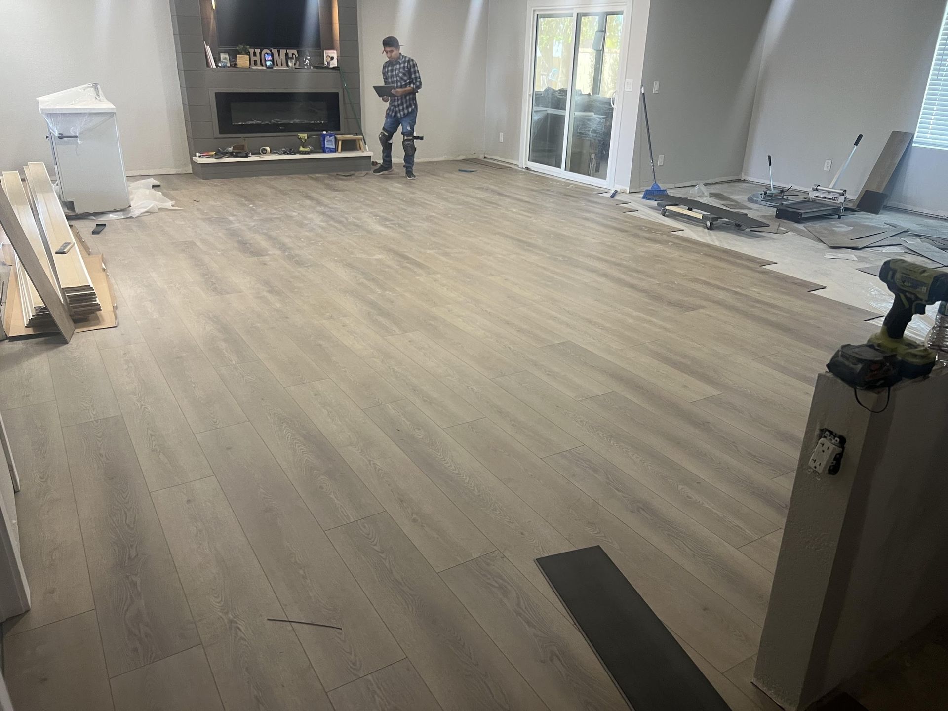 A man is standing in a living room with a wooden floor.