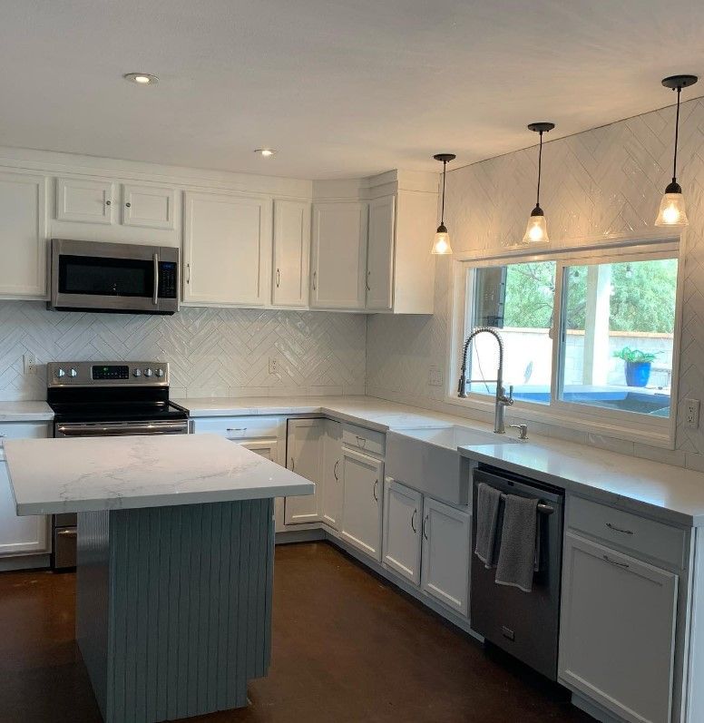 A kitchen with white cabinets , stainless steel appliances , a sink , and a stove.