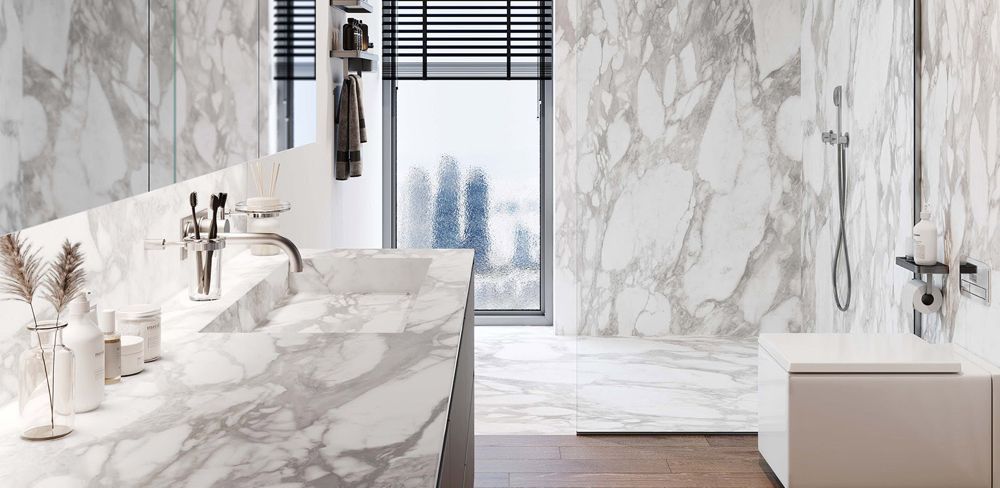 A bathroom with marble counter tops , a sink , and a shower.