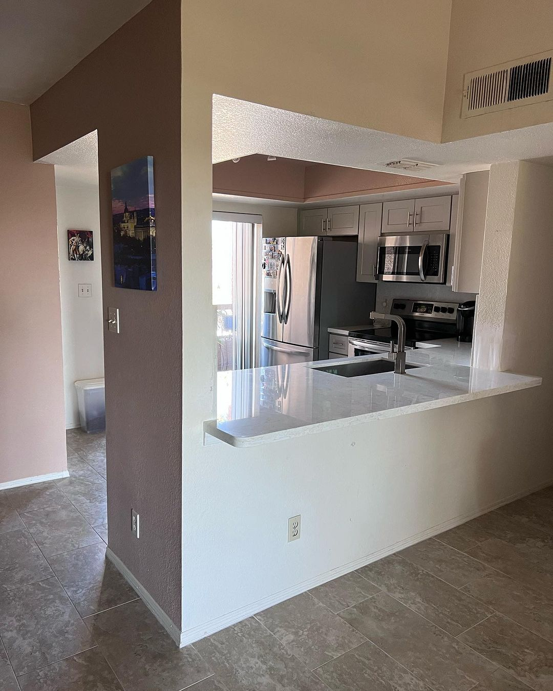 A kitchen with a sink , refrigerator , and microwave.