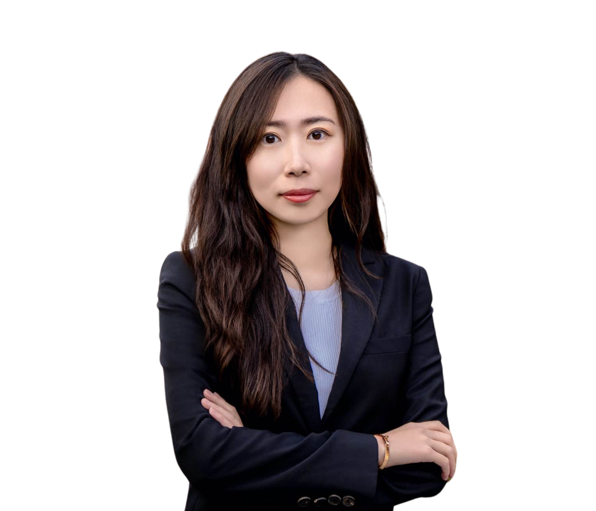 A woman in a suit is standing with her arms crossed and smiling.