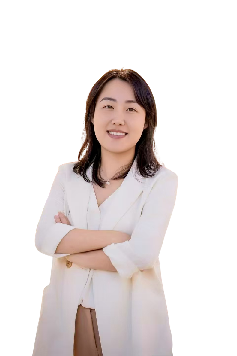 A woman in a suit is standing with her arms crossed and smiling.