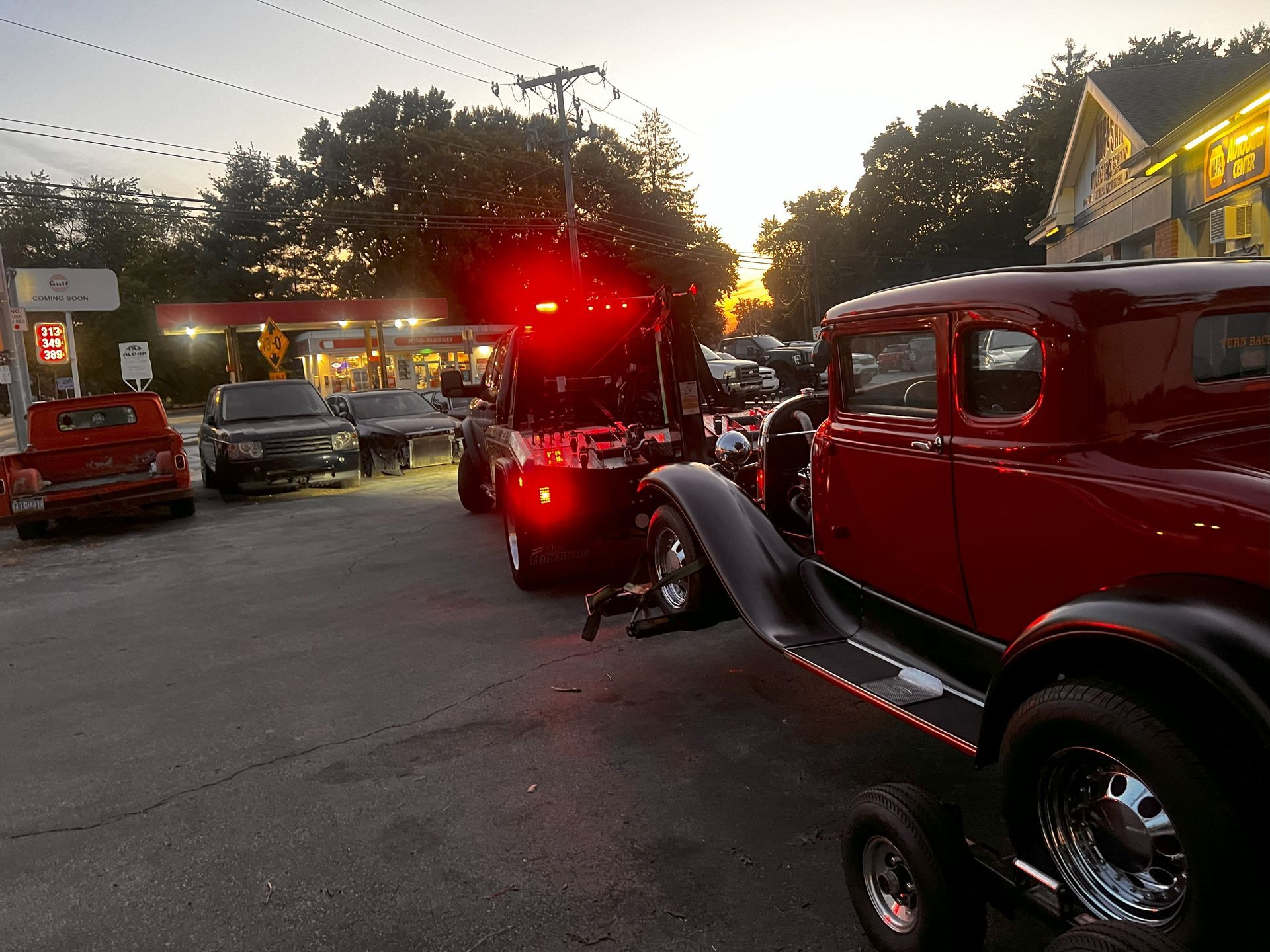 A red car is being towed by a tow truck