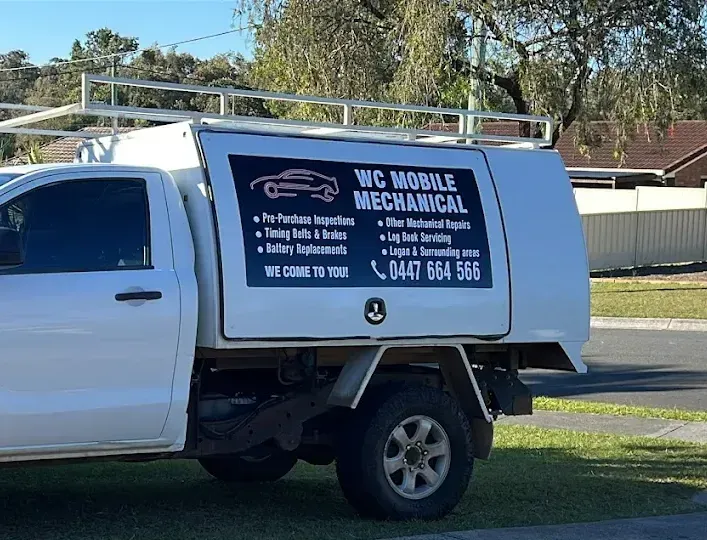 A mechanic in gloves is working on a car's brake system, using a wrench. The car is on a lift inside a garage. A mechanic in gloves is working on a car's brake system, using a wrench. The car is on a lift inside a garage.