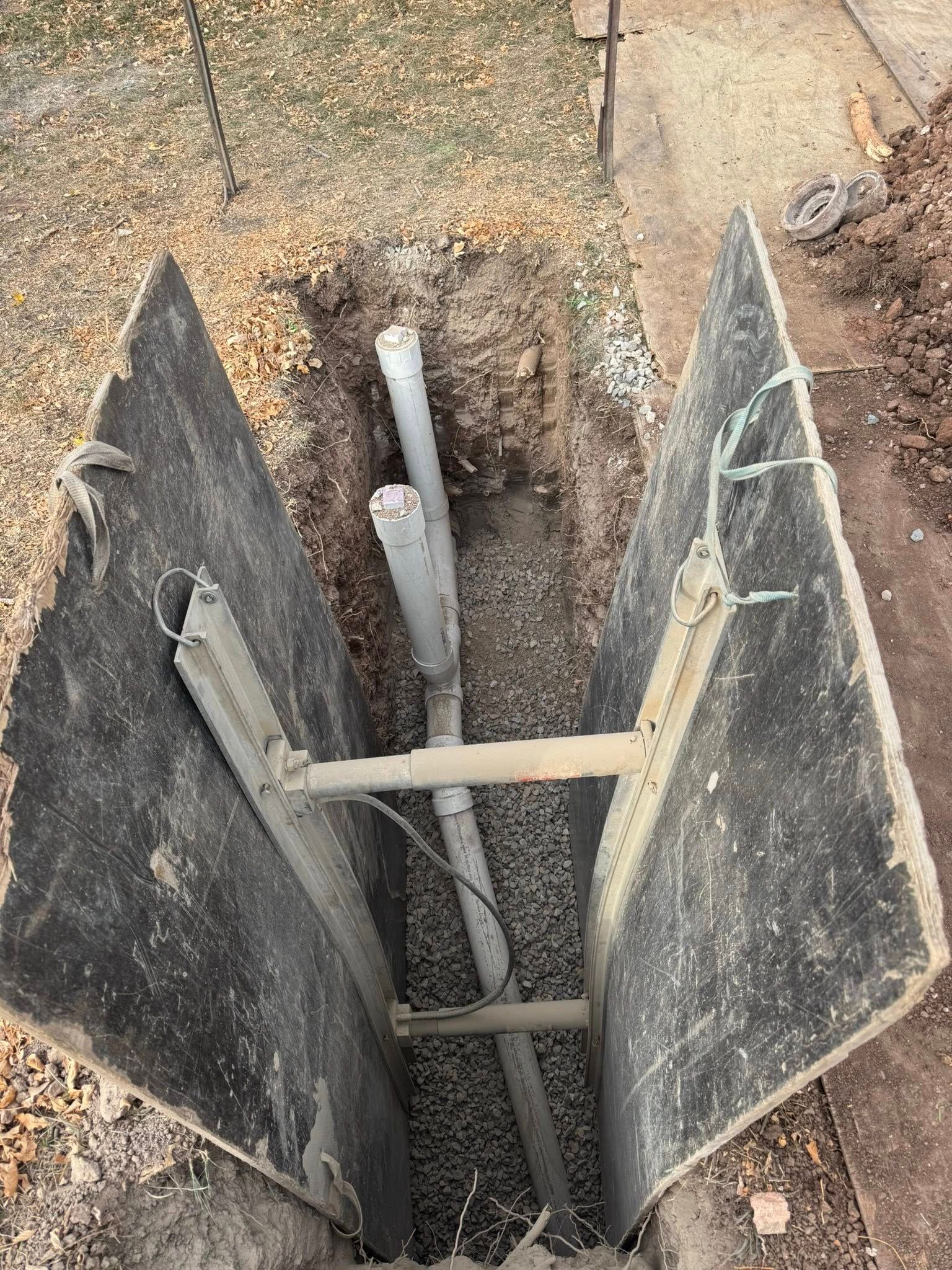 Woman in white shirt and apron smiles in front of plant.
