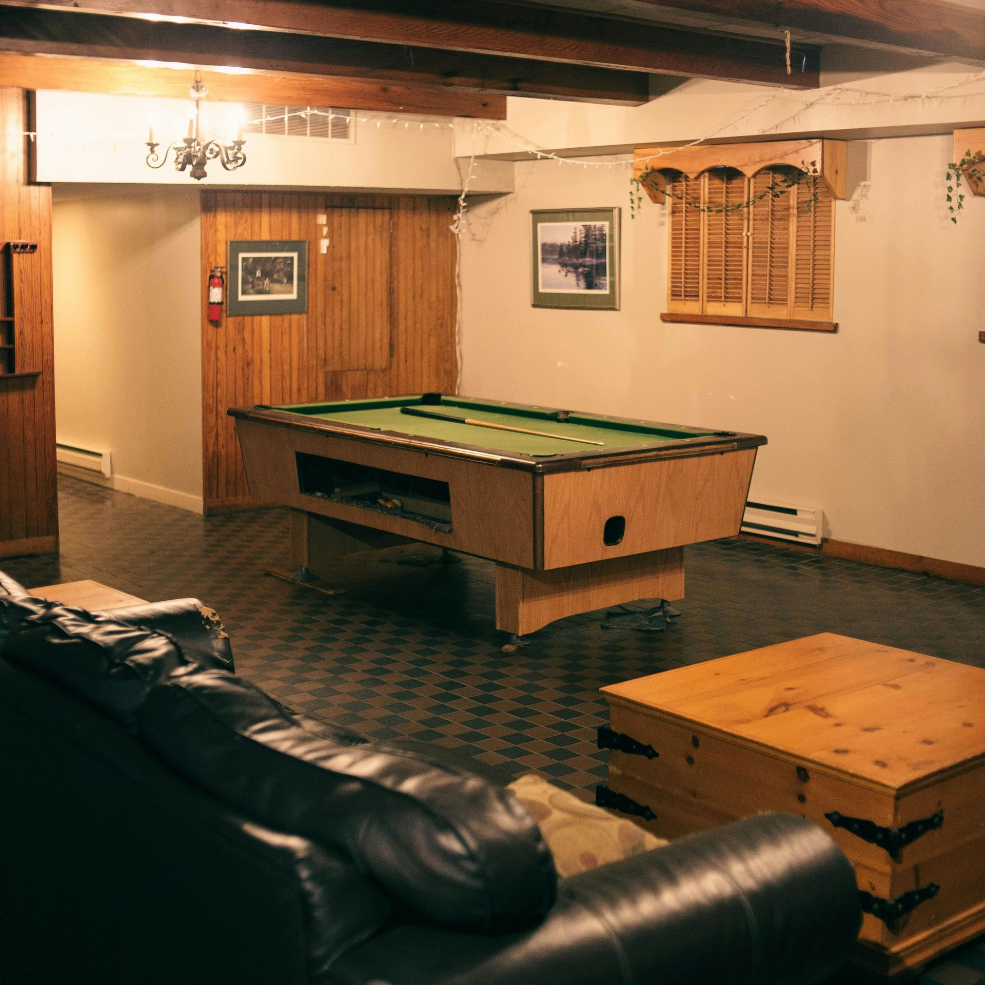 A basement with a pool table, leather sofa, and wooden chest. A basement with a pool table, leather sofa, and wooden chest.