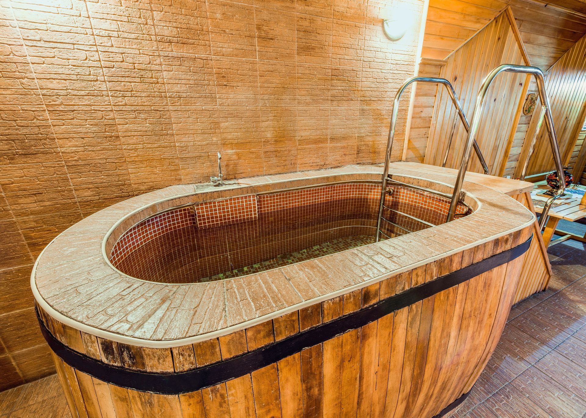 Wooden deck with a hot tub and umbrella next to a house with a stone facade and chimney, sunny day. Professional hot tub moving company Prescott AZ