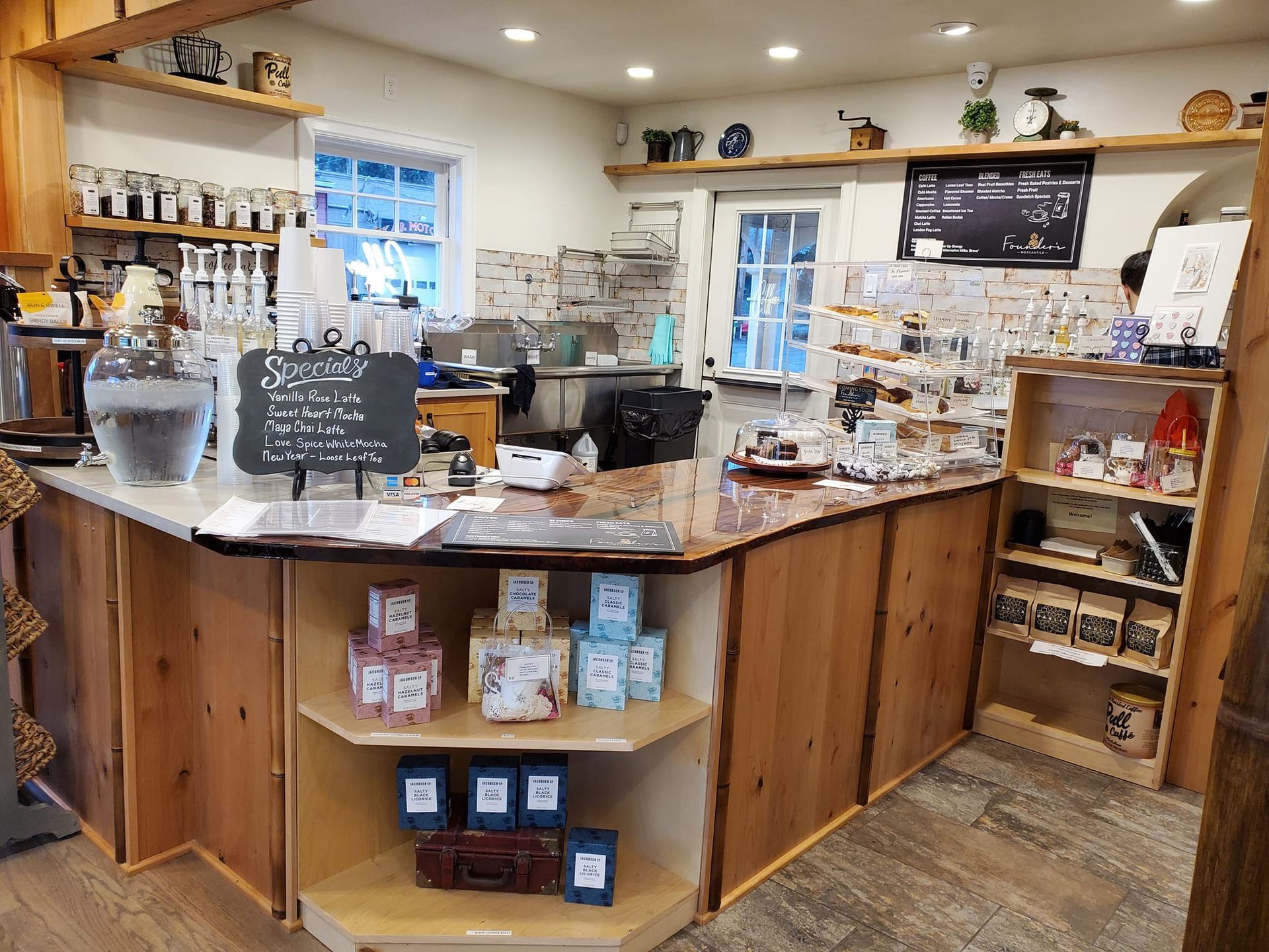 The inside of a coffee shop with a wooden counter and shelves.