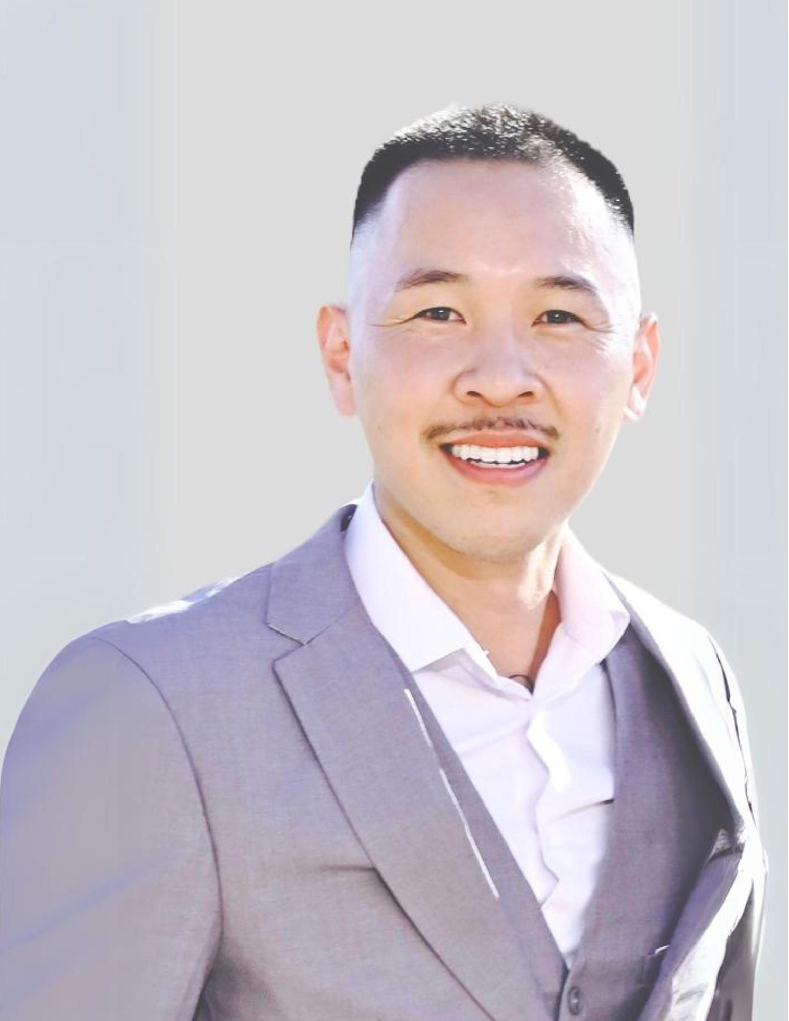 A woman is sitting at a desk with a laptop and a vase of flowers.