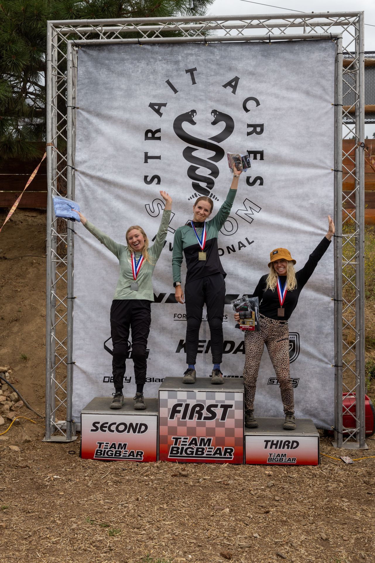 Podium with three women, first place in the center. 