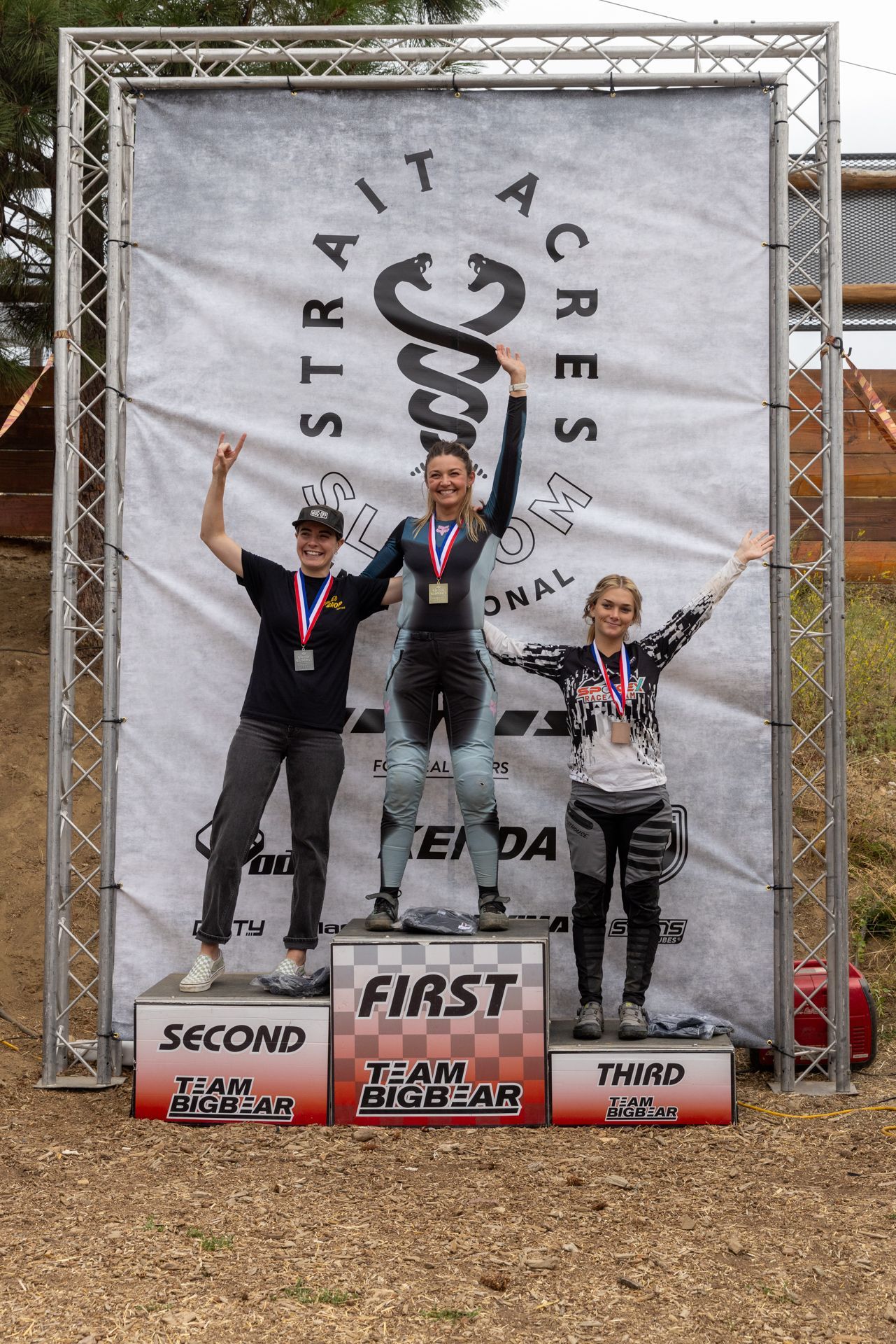 Podium with three women, arms raised in celebration. 