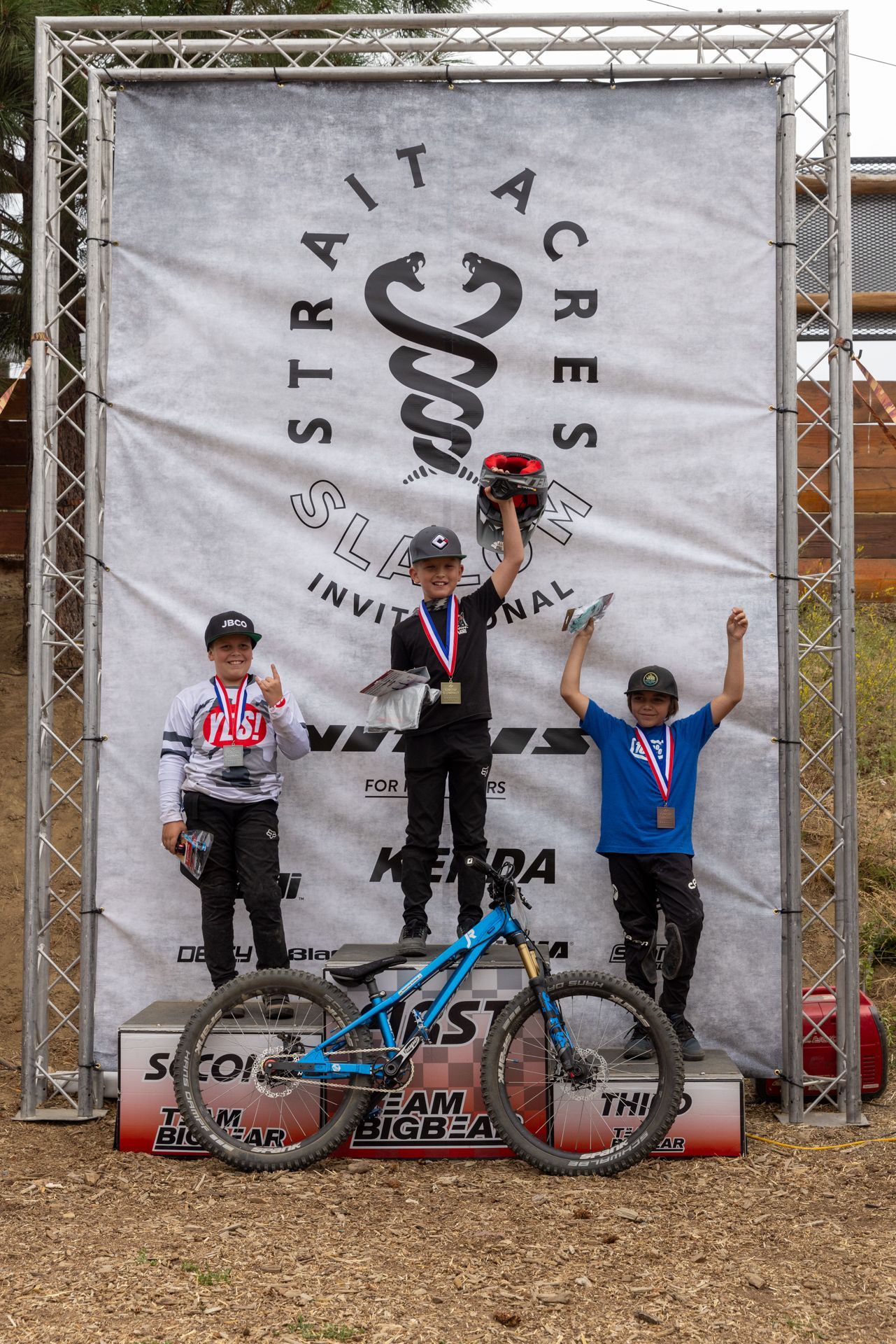 Three young boys on a podium with bikes after a Strait Acres Invitational race. 