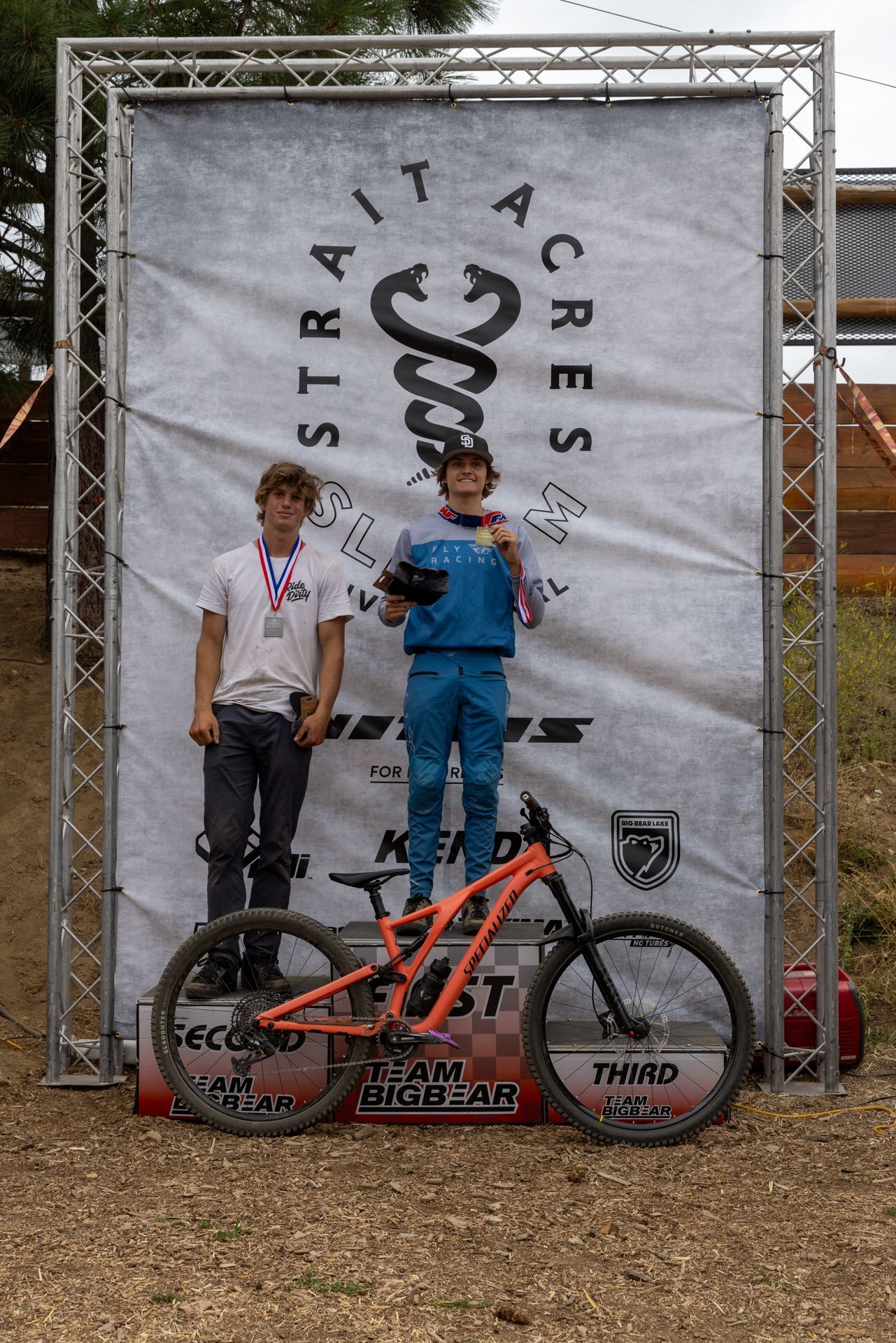 Two young mountain bikers on a podium after a race. The winner in blue 