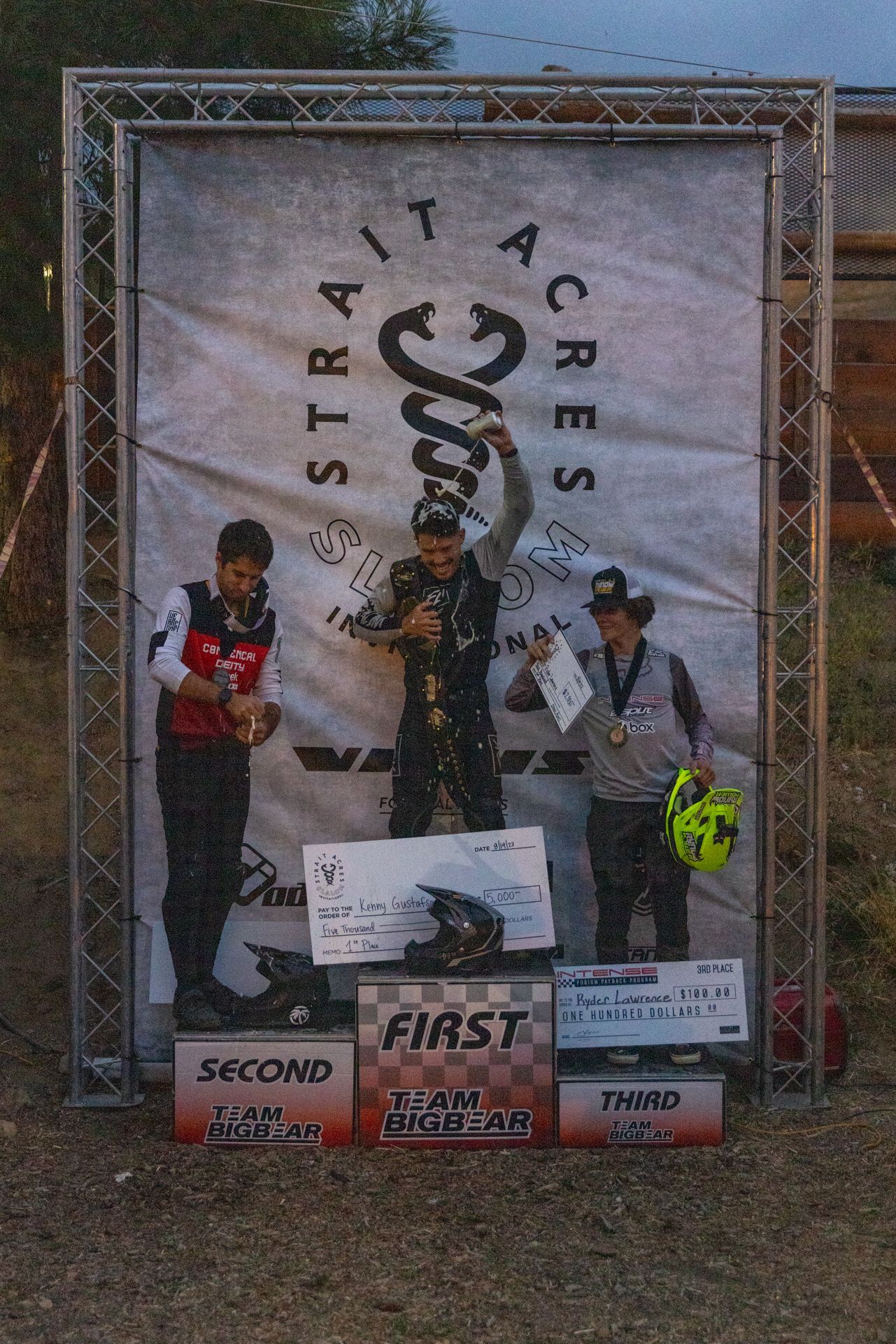 Podium with motocross riders at Strait Acres. First place winner raising trophy, others holding awards.