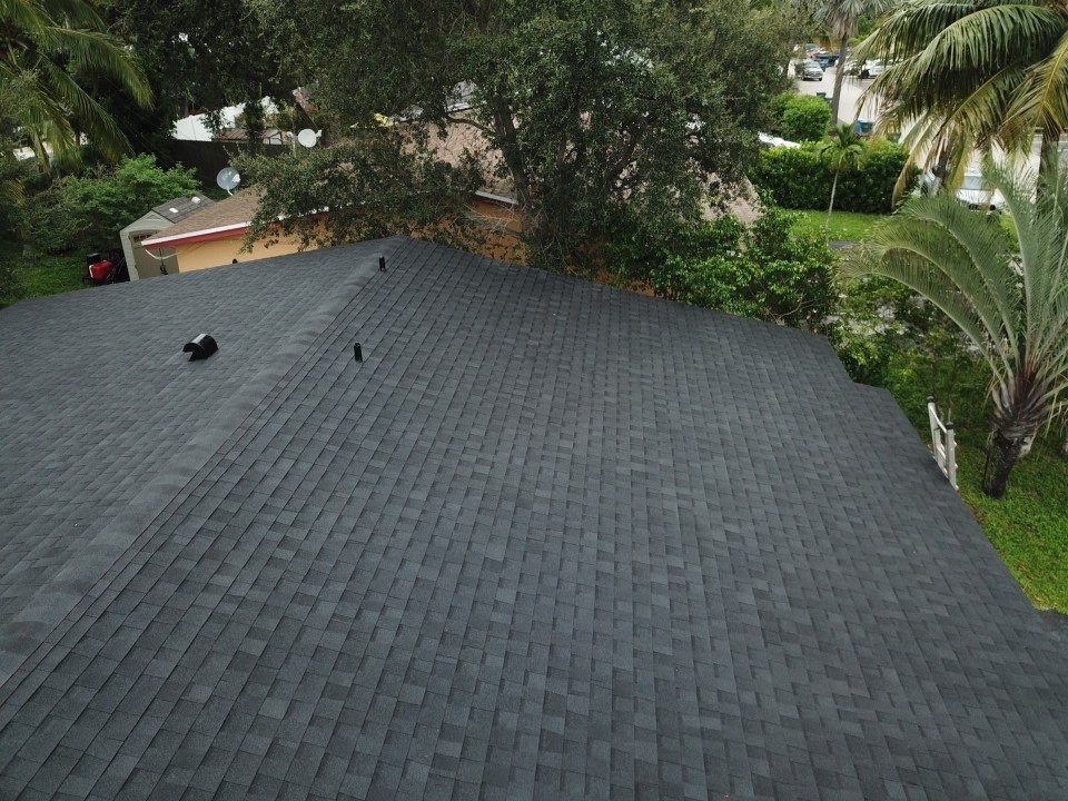 An aerial view of a roof with a lot of shingles and trees in the background.