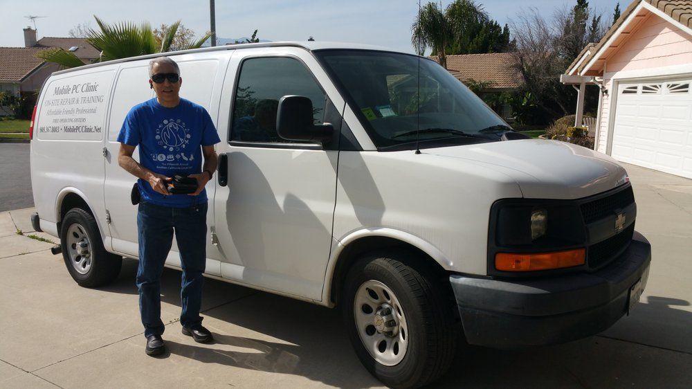 A man in a blue shirt is standing in front of a white van.