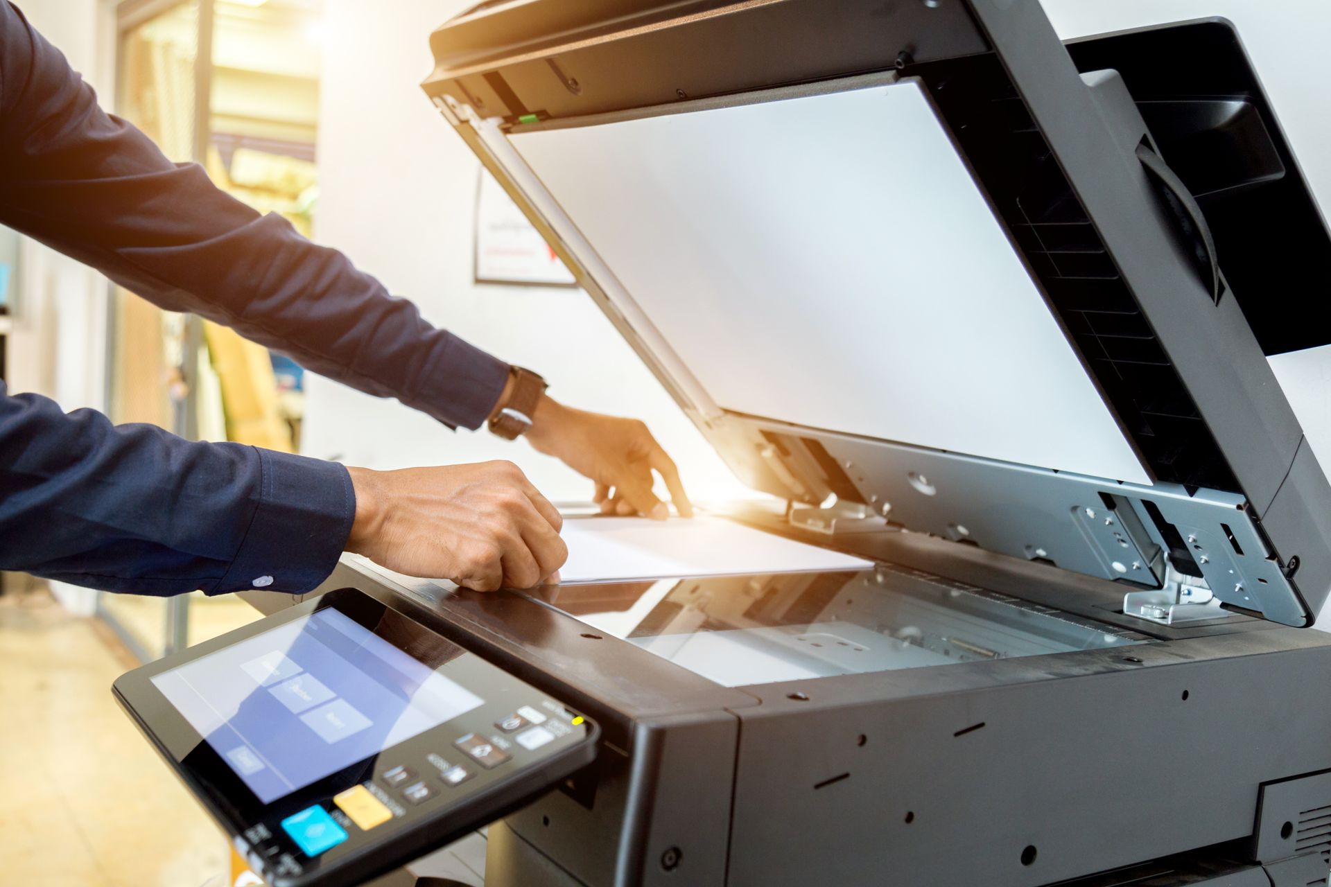 A man is using a copier to scan a piece of paper.
