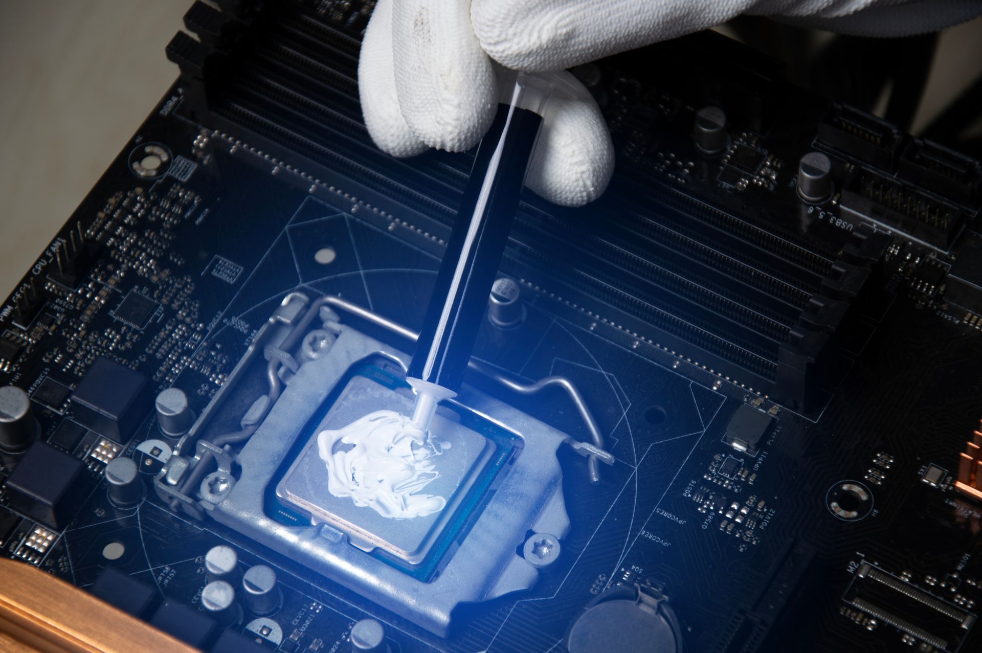 A person is applying thermal paste to a cpu on a motherboard.
