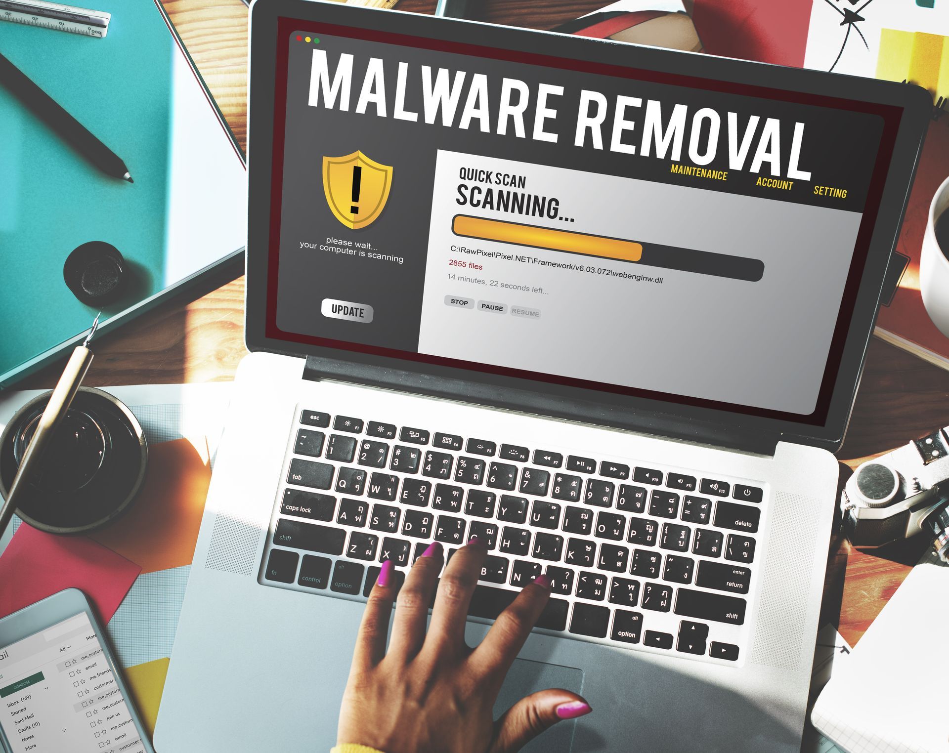 A woman is typing on a laptop computer with malware removal on the screen.