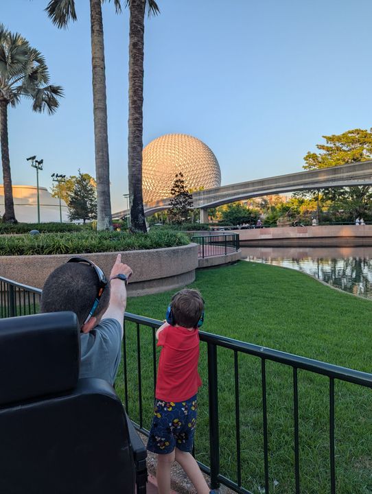 Man and child pointing at Spaceship Earth in Epcot.