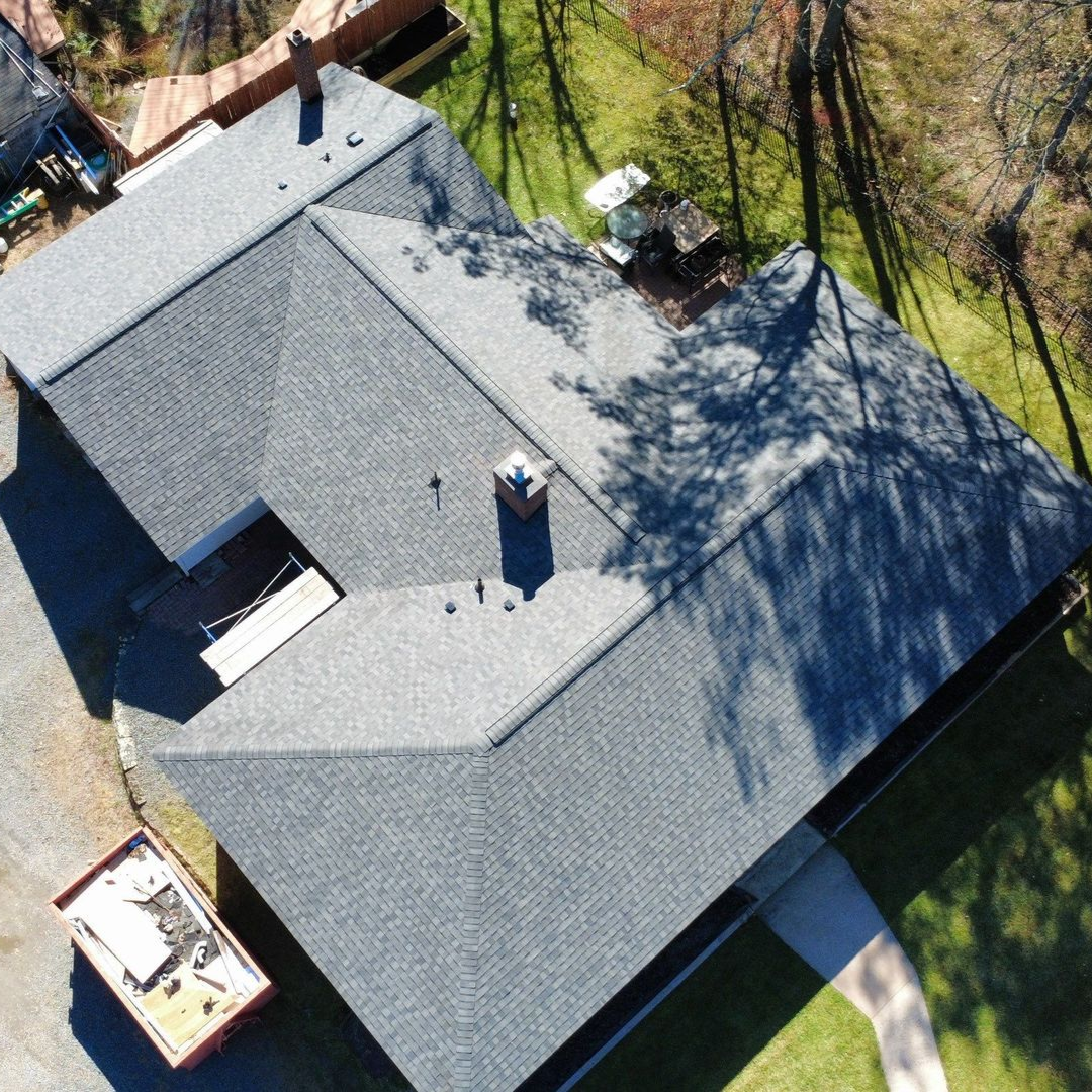 A person is holding a hammer in front of a roof A person is holding a hammer in front of a roof