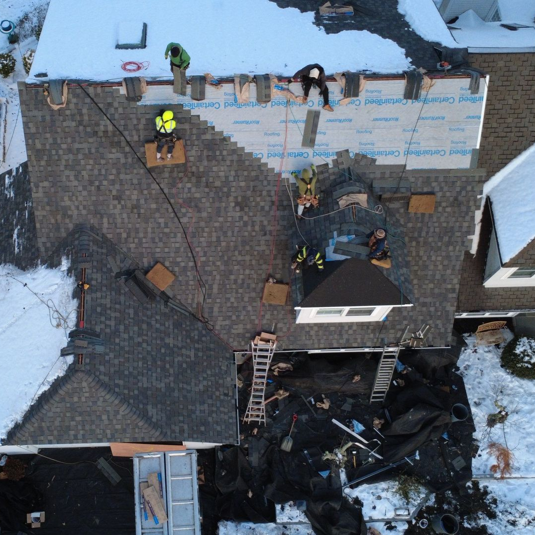 A person is holding a hammer in front of a roof