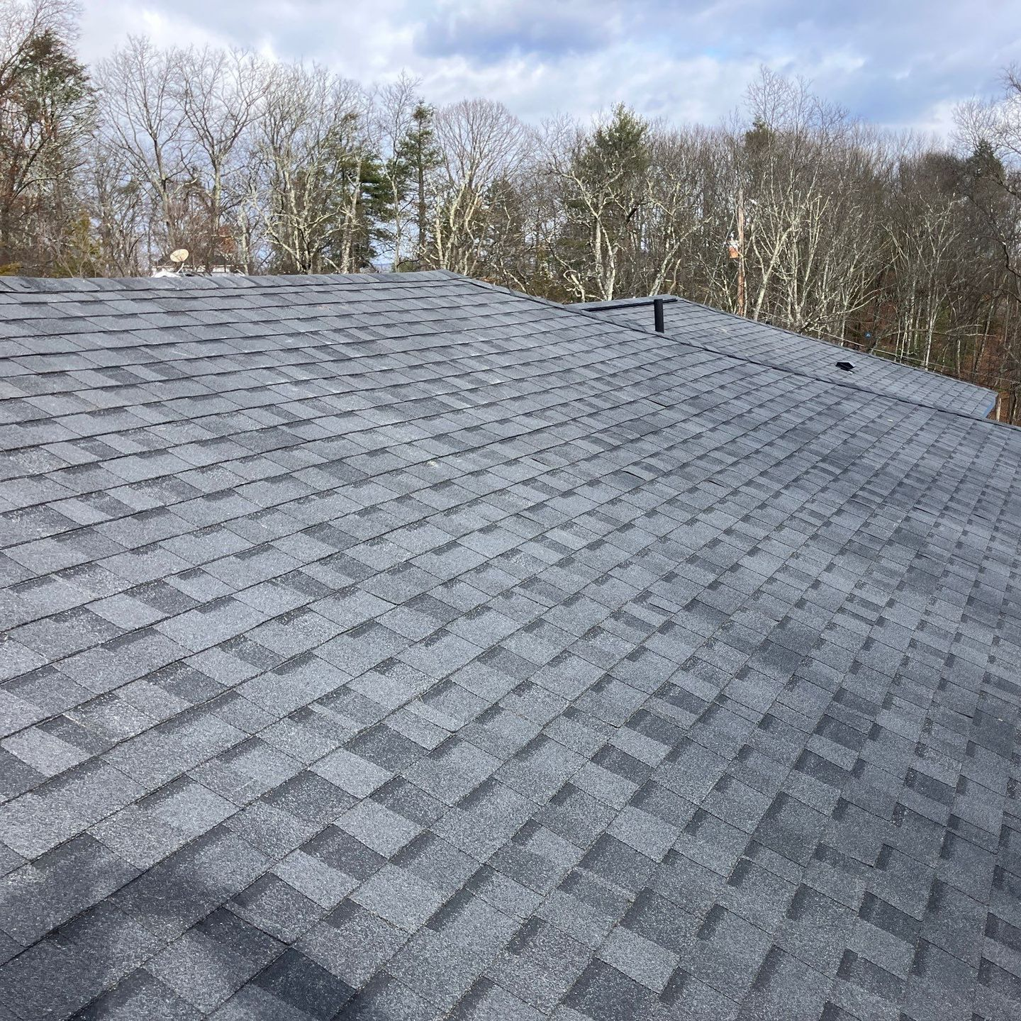 Aerial view of a house under construction with a gray shingle roof and green sheathing.