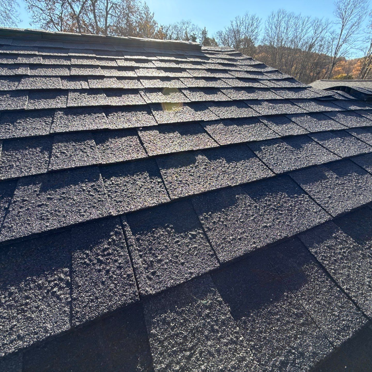 A person is holding a hammer in front of a roof