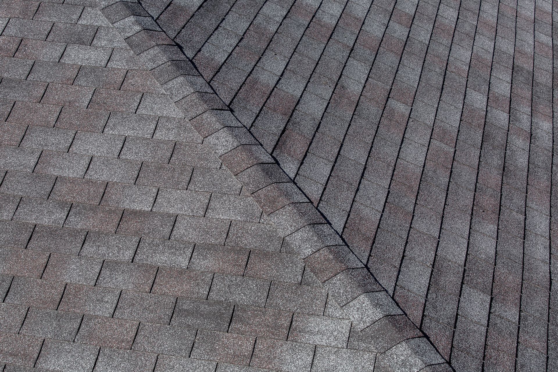 Dark gray asphalt shingle roof showing the intersection of two roof planes.