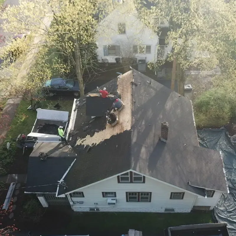 An aerial view of a house with people working on the roof