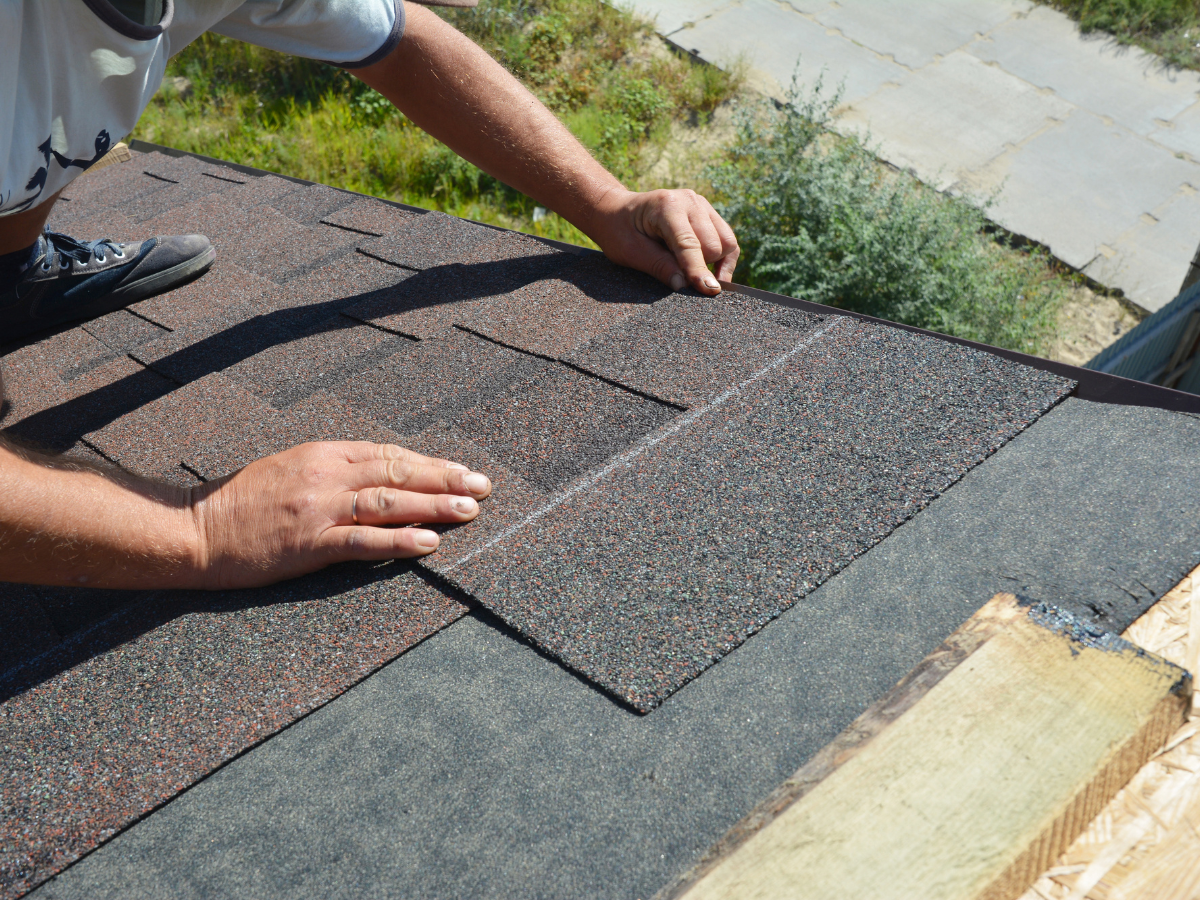 A man is installing shingles on a roof.