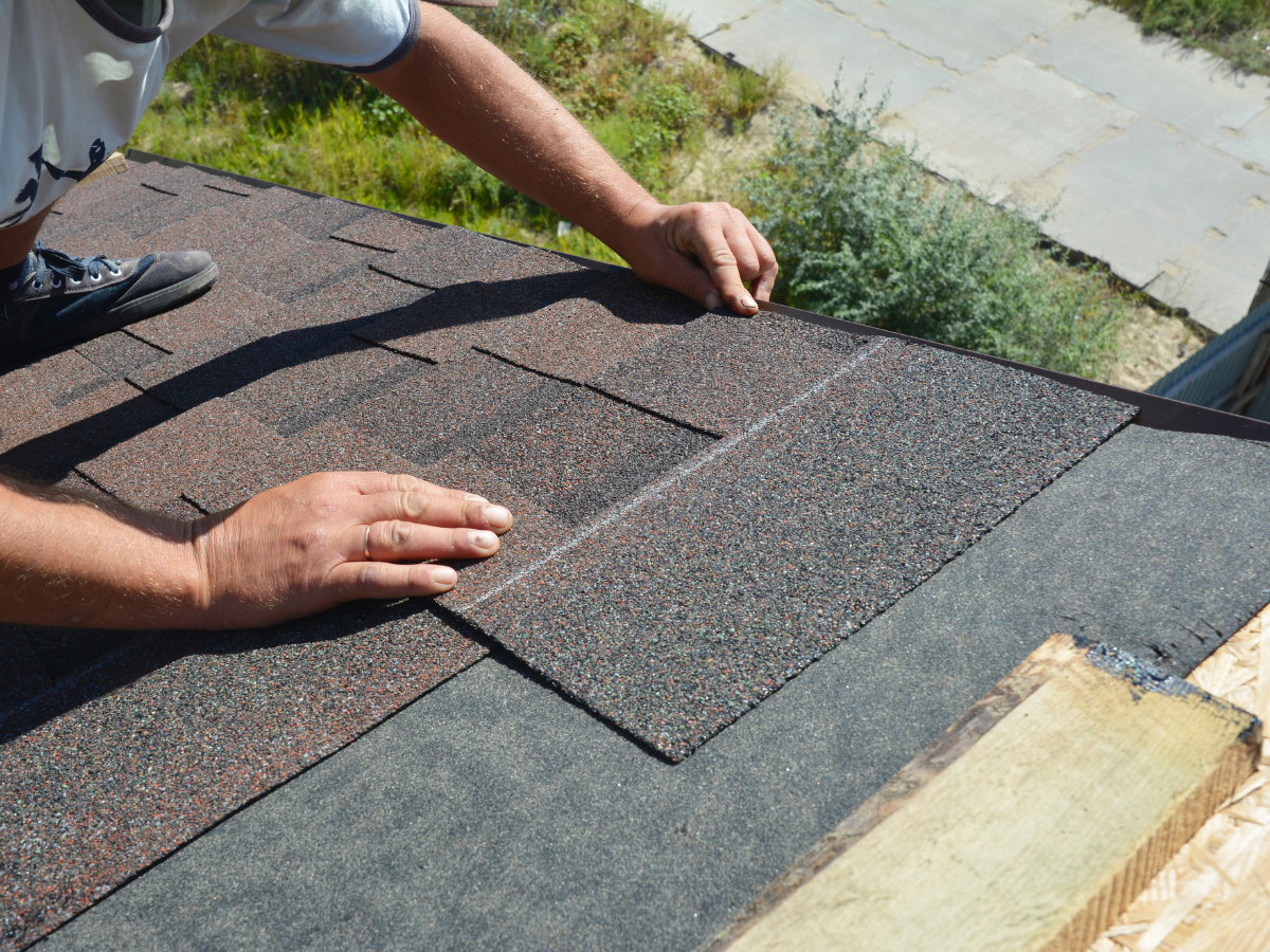 A man is laying shingles on a roof.