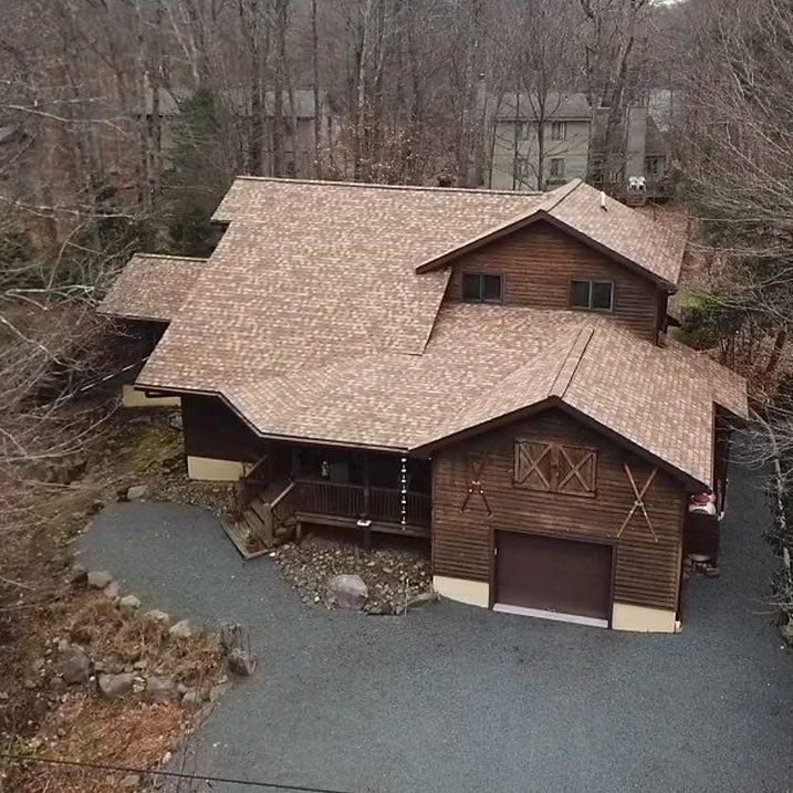An aerial view of a large wooden house in the middle of a forest.